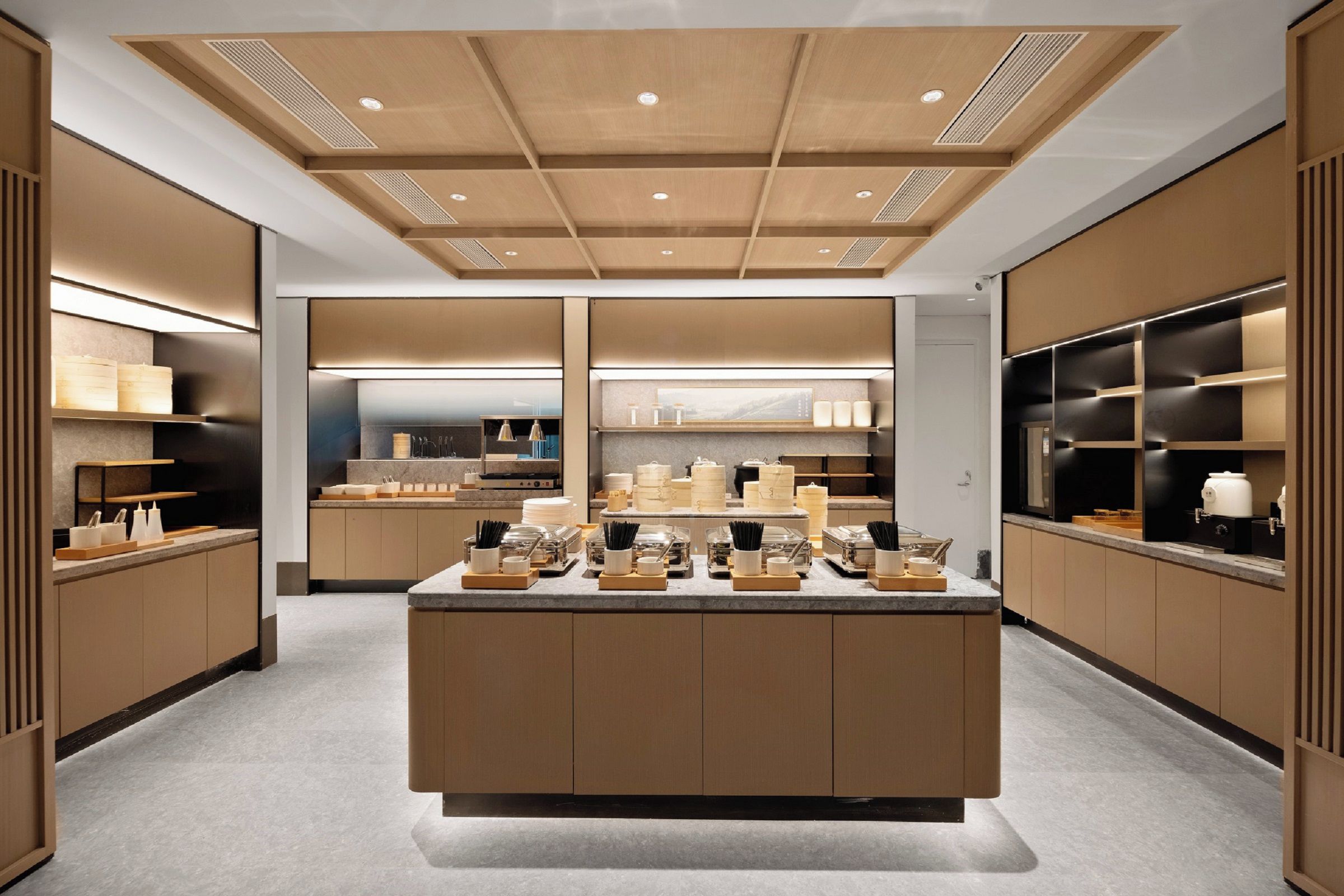 A modern kitchen with wooden cabinetry, a central island with various kitchen items, and built-in appliances.