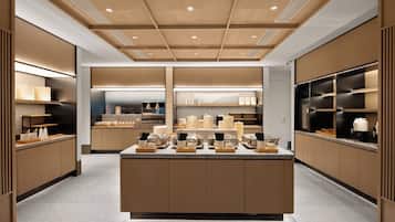 A modern kitchen with wooden cabinetry, a central island with various kitchen items, and built-in appliances.