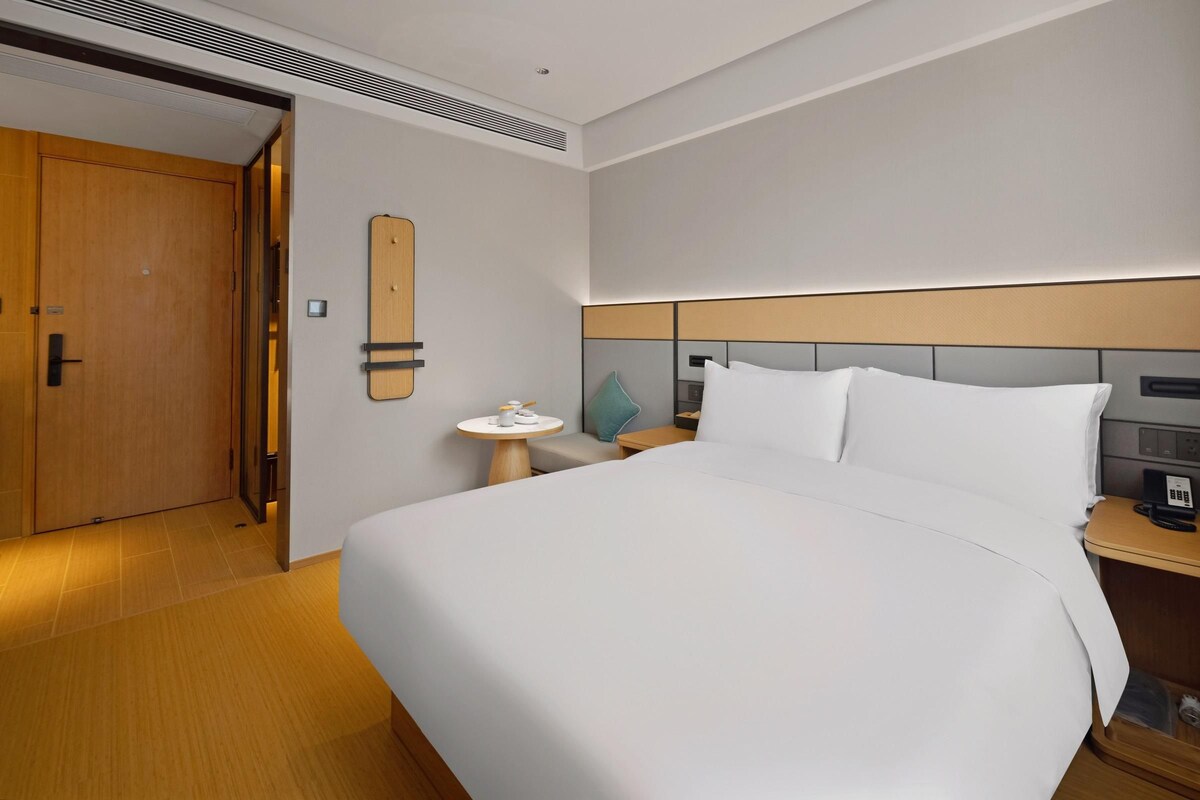 Ein Hotelzimmer mit einem großen Bett, einem Nachttisch, einem kleinen runden Tisch und einer Tür.