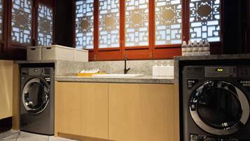 A laundry area with two washing machines, a sink, and a countertop with bottles.