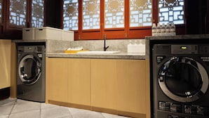 A laundry area with two washing machines, a sink, and a countertop with bottles. - Ji Hotel Chongqing Bishan Cbd Xiuhu Park (Chongqing)