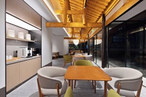 A modern interior with a wooden ceiling, a kitchen area with a coffee machine, and a seating area with chairs and a table. - Ji Hotel Chongqing Bishan Cbd Xiuhu Park (Chongqing)
