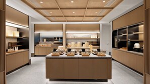 A modern kitchen with wooden cabinetry, a central island with various kitchen items, and built-in appliances. - Ji Hotel Chongqing Bishan Cbd Xiuhu Park (Chongqing)