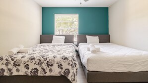 A bedroom with two beds, a ceiling fan, and a window with blinds.