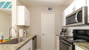 A compact kitchen with a sink, stove, microwave, and cabinets.