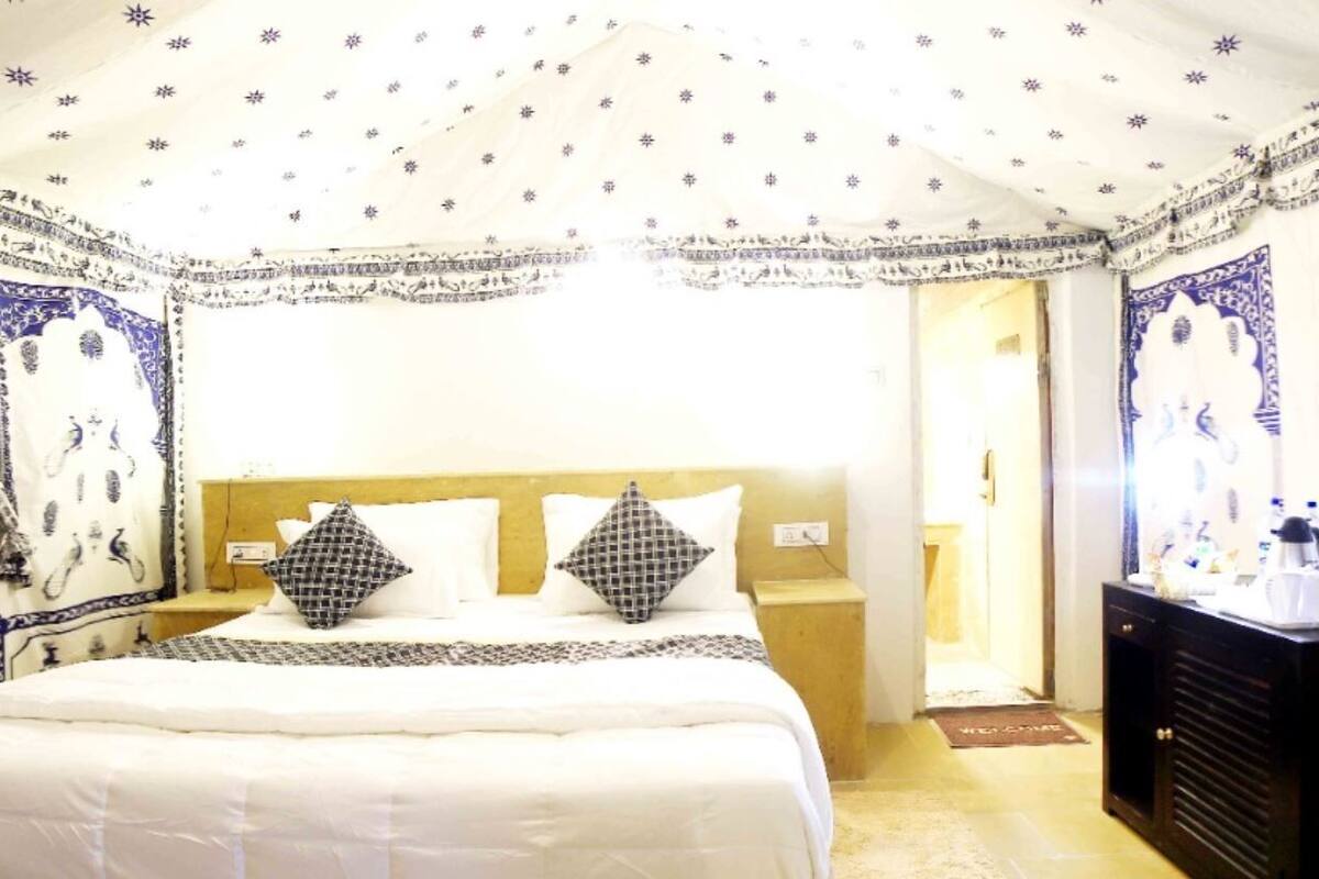 A hotel room with a bed, nightstands, a dresser, and a view of the outside.