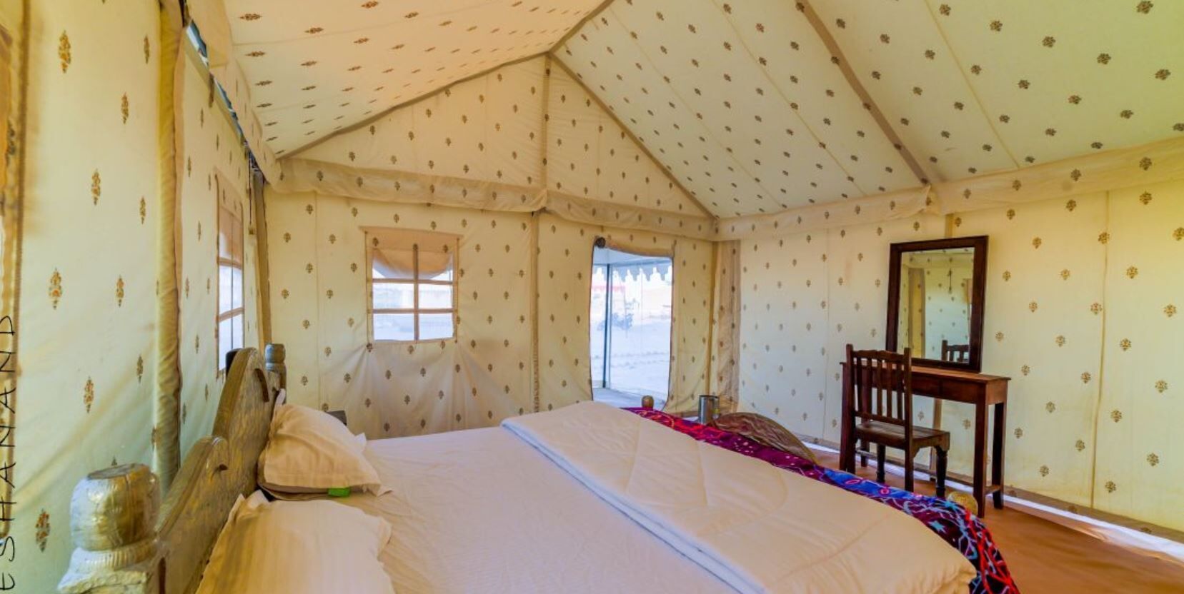 A tent-style room with a bed, a desk, and a chair.