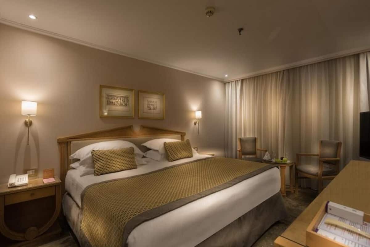 Una camera d'albergo con un letto grande, abat-jour, una scrivania, una sedia e un televisore.
