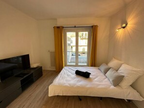 A bedroom with a bed, a TV, a radiator, and a window with curtains. - Sion Central Station proche toutes commodités by Interhome (Sion)