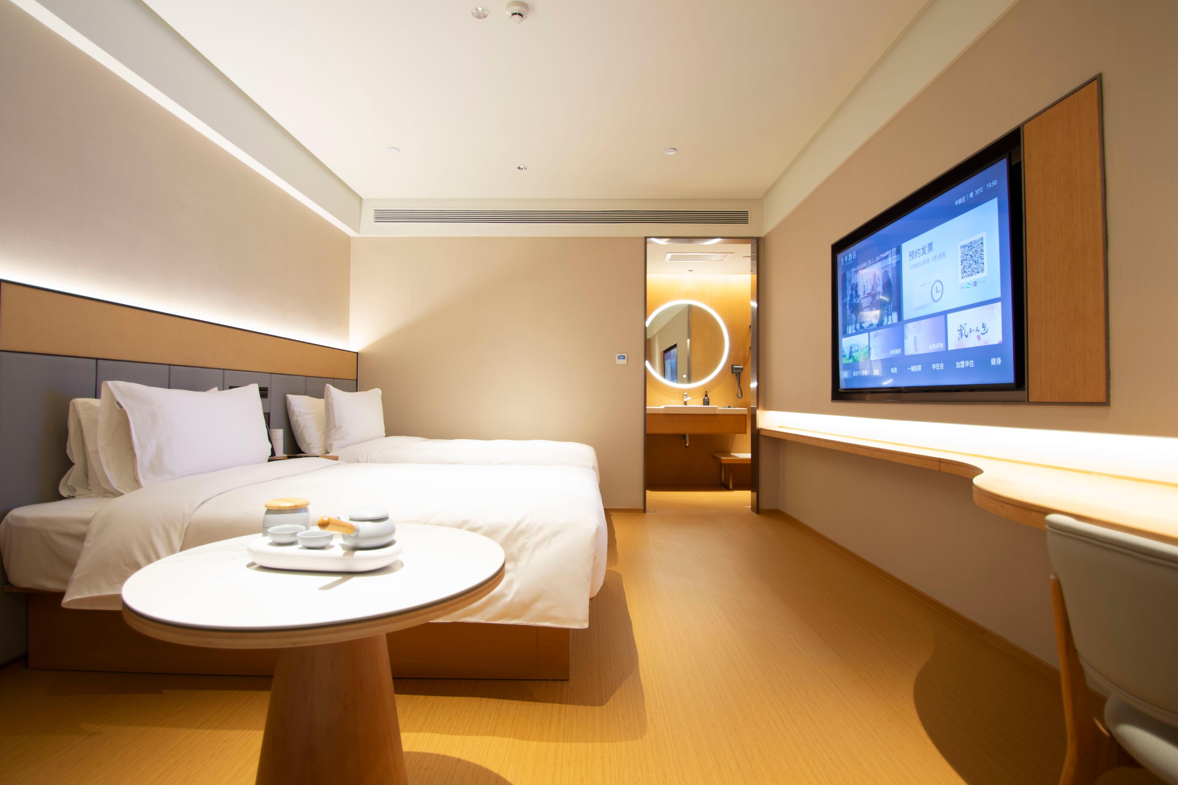 Una habitación de hotel moderna con una cama, una mesita de noche y un televisor montado en la pared.