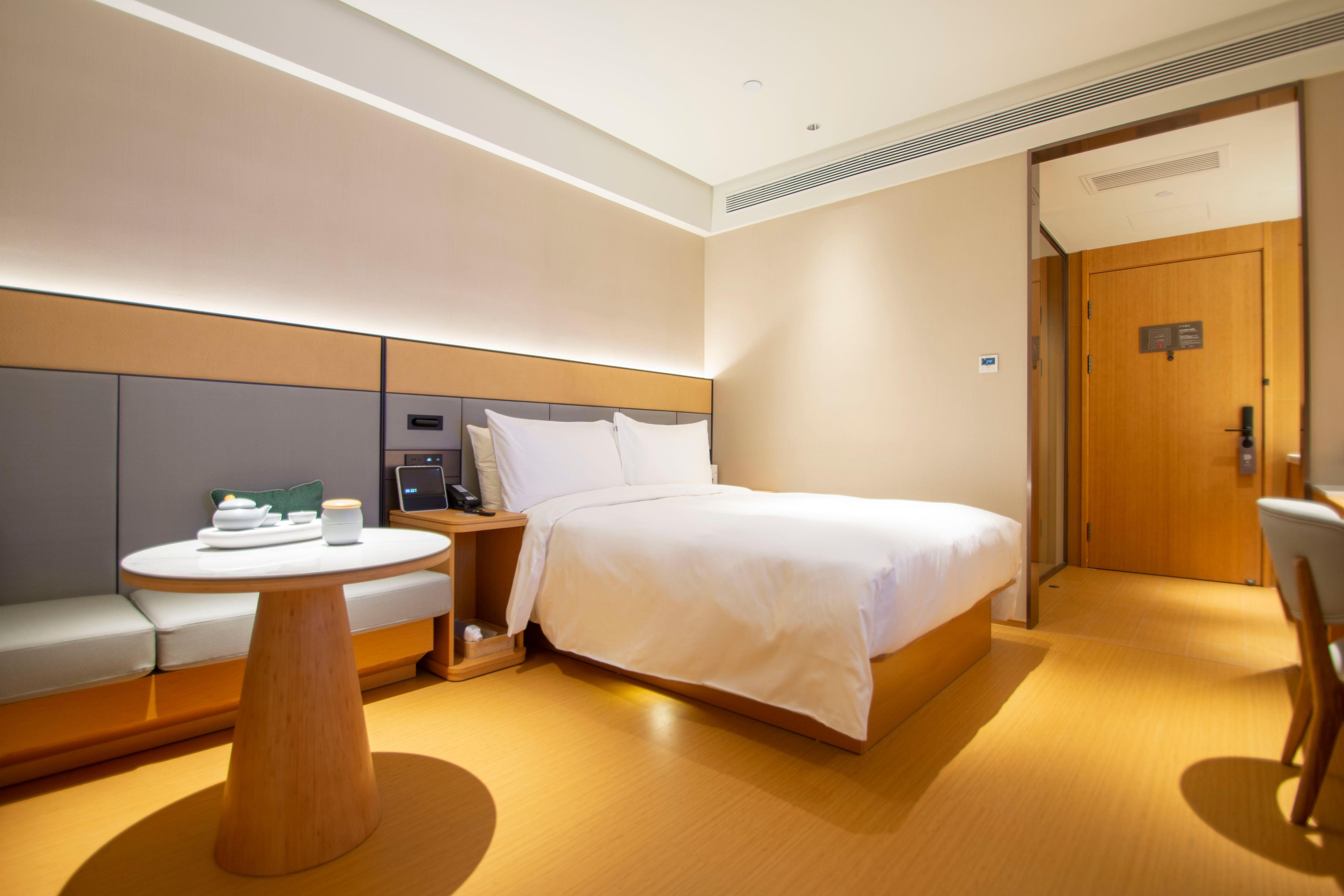 Ein Hotelzimmer mit einem Bett, einem runden Holztisch, einer Couch und einer Tür.