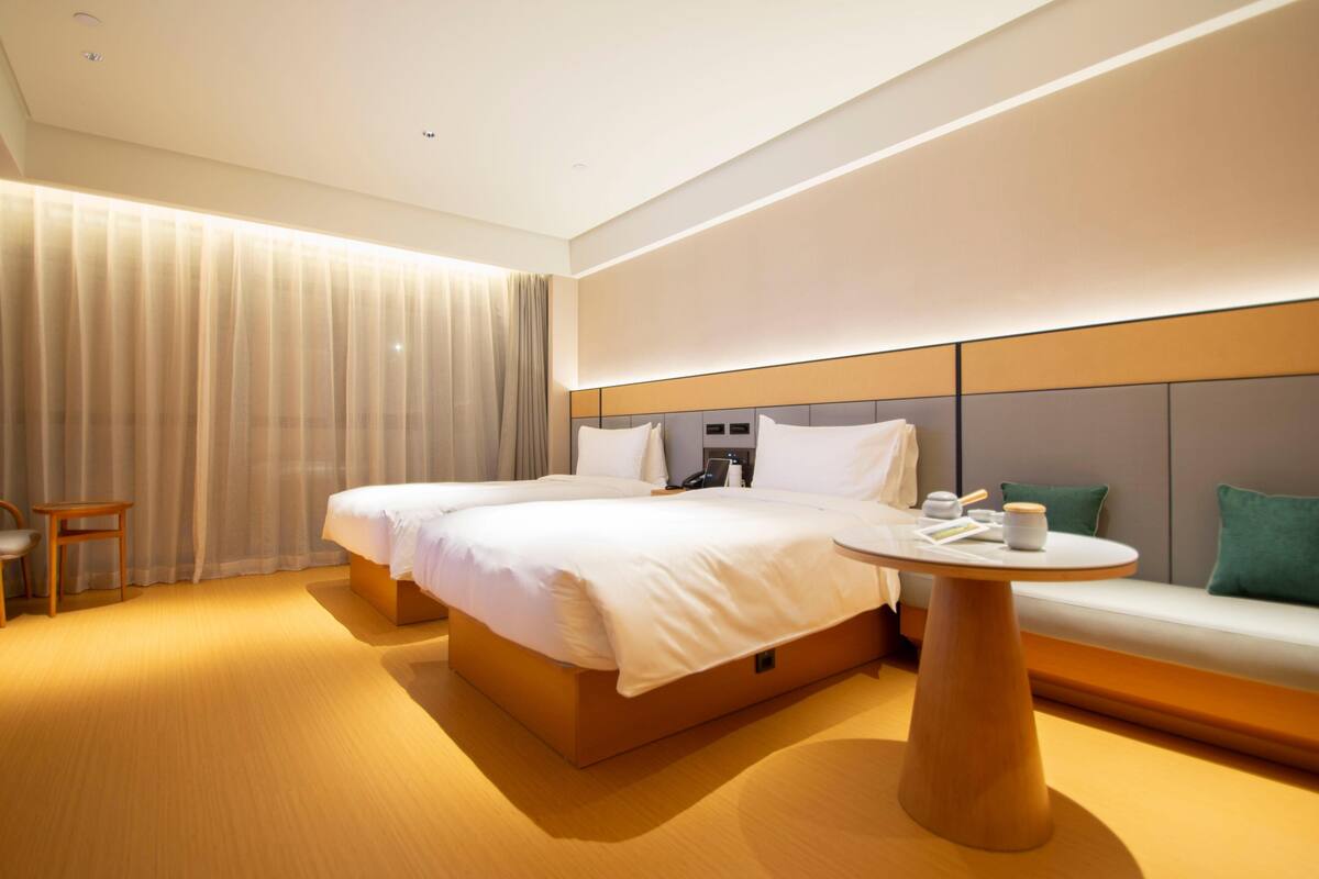 Ein Hotelzimmer mit einem großen Bett, Nachttischen, einem runden Tisch, einer Couch und einem Vorhang.