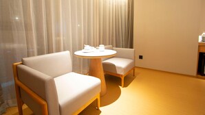 A modern hotel room with a round wooden table, two cushioned chairs, and a large window with sheer curtains. - Ji Hotel Zhengzhou Agricultural Road Shenglong Tia (Zhengzhou)