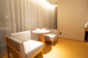 A modern hotel room with a round wooden table, two cushioned chairs, and a large window with sheer curtains. - Ji Hotel Zhengzhou Agricultural Road Shenglong Tia (Zhengzhou)