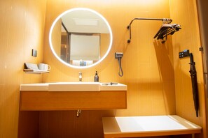 A bathroom with a round mirror, a sink, a towel rack, and a handheld showerhead. - Ji Hotel Zhengzhou Agricultural Road Shenglong Tia (Zhengzhou)