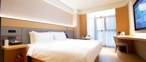 A modern hotel room with a large bed, a desk, a chair, and a TV.