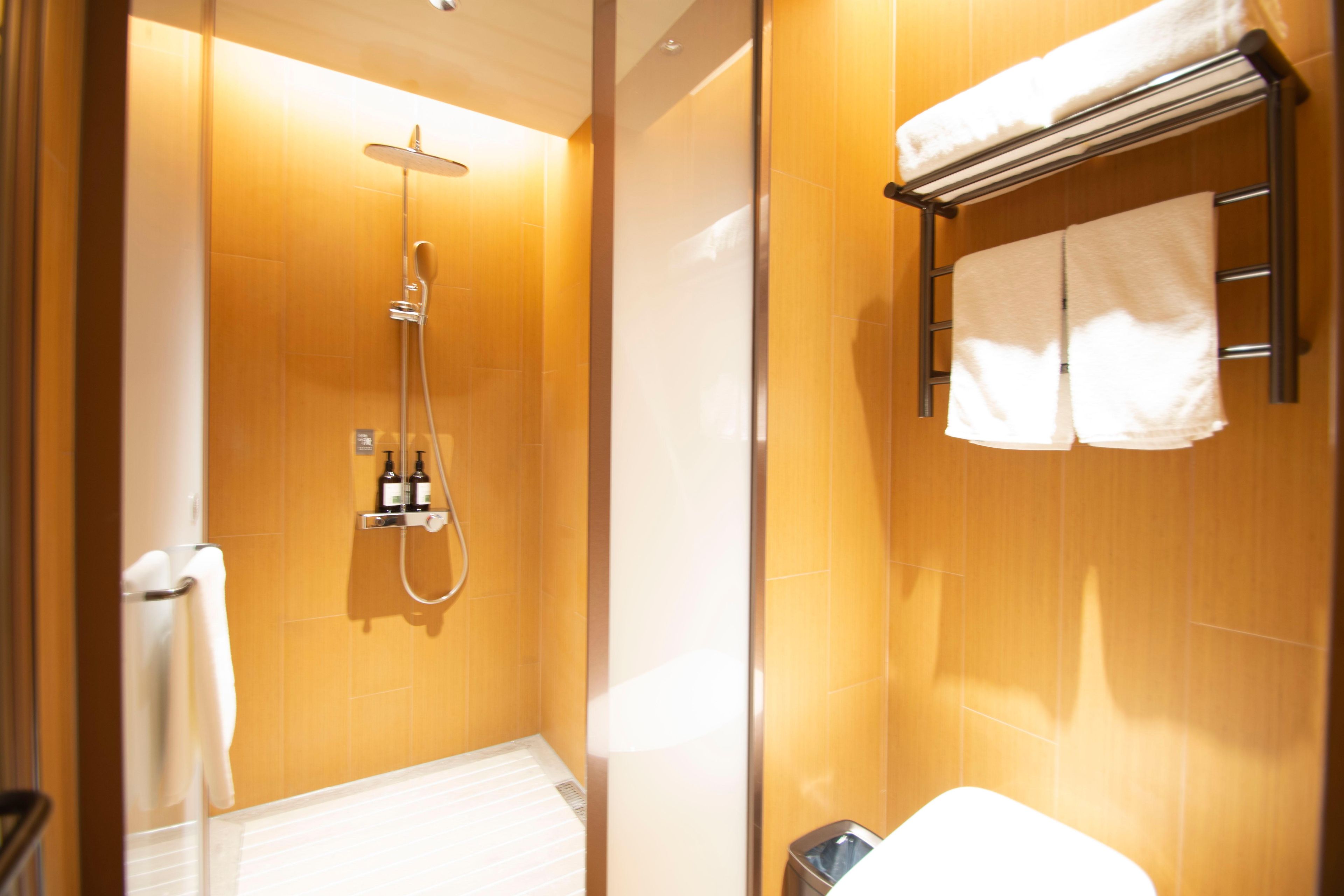A bathroom with a shower, a towel rack, and a toilet.