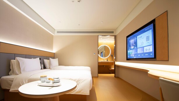 A modern hotel room with a bed, bedside table, and a TV mounted on the wall. - Ji Hotel Zhengzhou Agricultural Road Shenglong Tia (Zhengzhou)