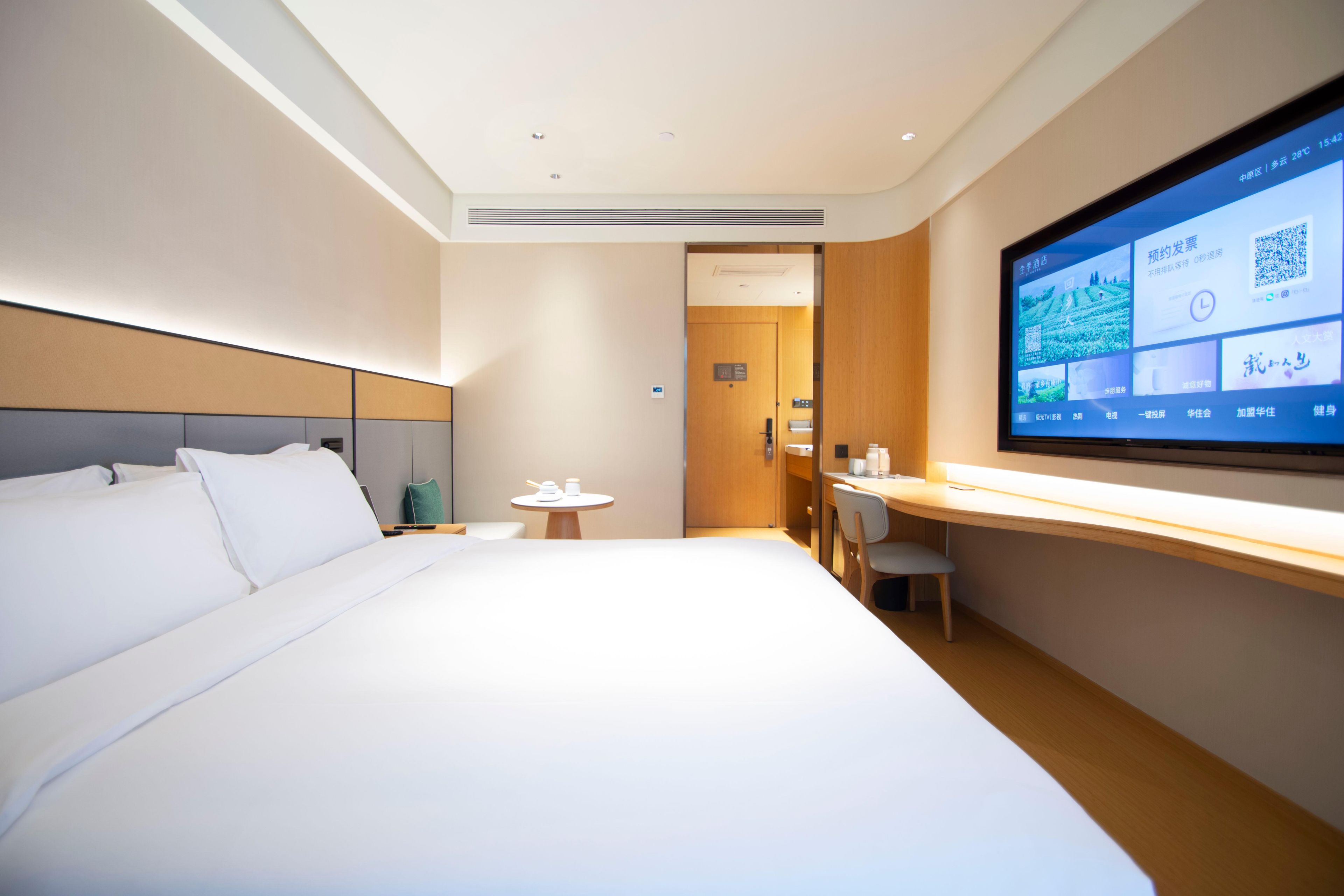 Une chambre d’hôtel moderne équipée d’un grand lit, d’un bureau et d’un téléviseur qui affiche des informations.