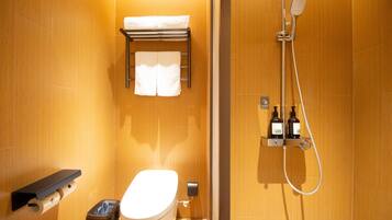 Une salle de bain comprenant des toilettes, un porte-serviettes, une douche avec un pommeau de douche amovible et un distributeur de savon.