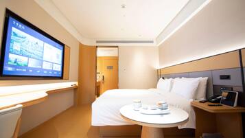 A hotel room with a bed, bedside table, TV, and a desk with a chair.