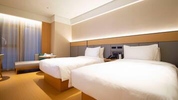 A hotel room with two beds, a desk, a chair, and a large window with curtains.