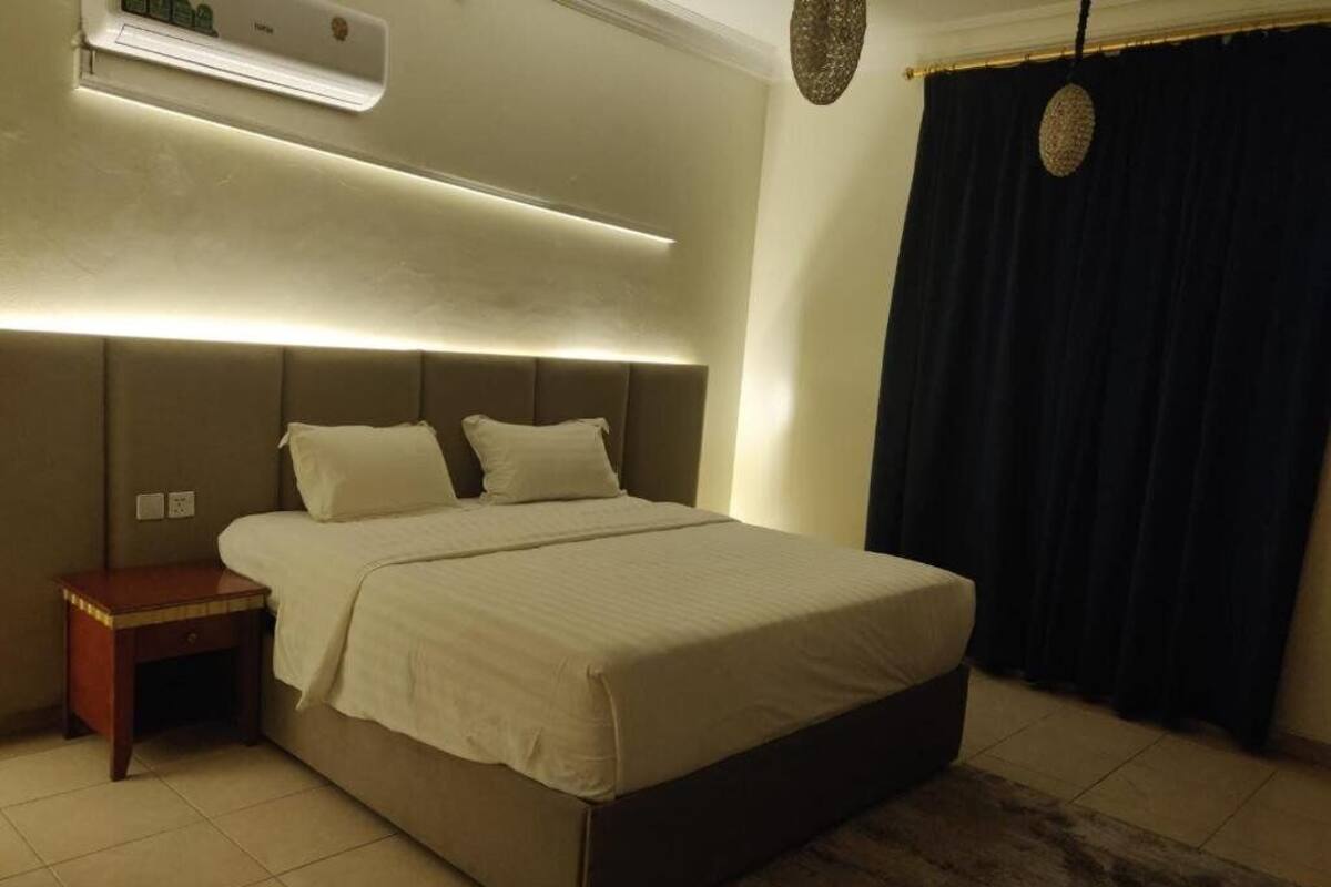 A bedroom with a bed, bedside table, and an air conditioning unit.