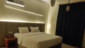 A bedroom with a bed, bedside table, and an air conditioning unit. - Golden Dana Agadir (Jizan)