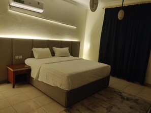 A bedroom with a bed, bedside table, and an air conditioning unit. - Golden Dana Agadir (Jizan)