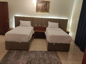 A double bed room with a headboard, a bedside table, a rug, and a painting on the wall. - Golden Dana Agadir (Jizan)