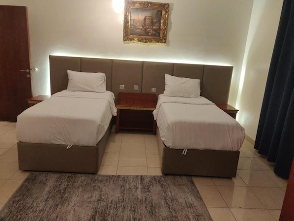 Habitación doble con cama, mesita de noche, alfombra y un cuadro en la pared.