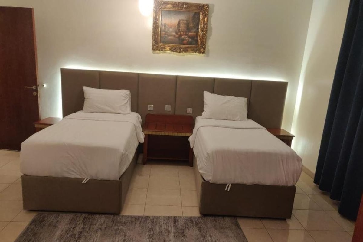 Habitación doble con cama, mesita de noche, alfombra y un cuadro en la pared.