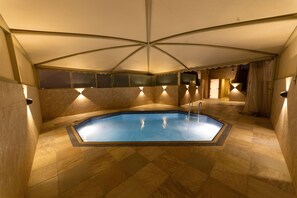 Una piscina interior amb sòl de rajola i sostre amb un disseny geomètric únic.
