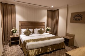 Una habitació d'hotel amb un llit gran, taules de nit, una estant i una planta en test.