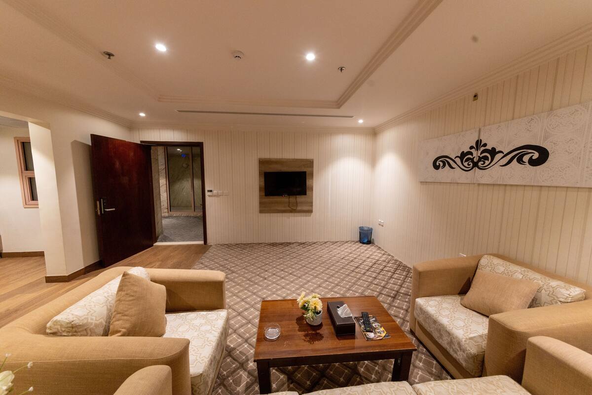 Una sala de estar moderna con un televisor de pantalla plana, una mesa de centro con un florero y un control remoto, y dos sofás.