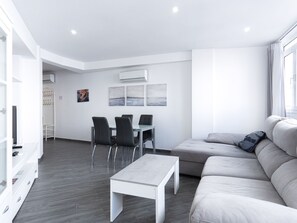 A modern living room with a sofa, a dining table with chairs, and a small white table. - Apartment  by Interhome (Nerja)