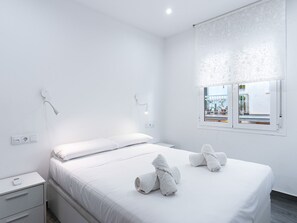 Une chambre moderne avec un lit simple, des tables de chevet, une fenêtre avec vue et une prise de courant.
