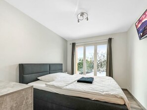 Ein Schlafzimmer mit Bett, einem Fenster mit Vorhängen und einer Deckenleuchte.