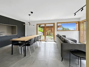 Une cuisine moderne avec une table et des chaises, un canapé et une grande fenêtre donnant sur un beau paysage.