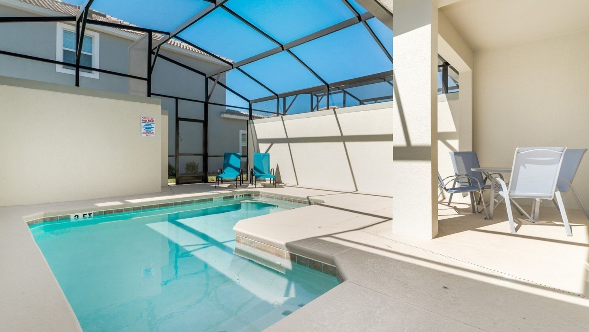 A swimming pool with a glass ceiling, blue chairs, and a pool table.