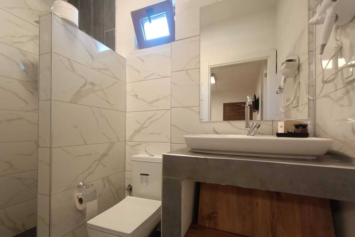 Ein Badezimmer mit Toilette, Waschbecken mit Spiegel und einer Duschkabine.