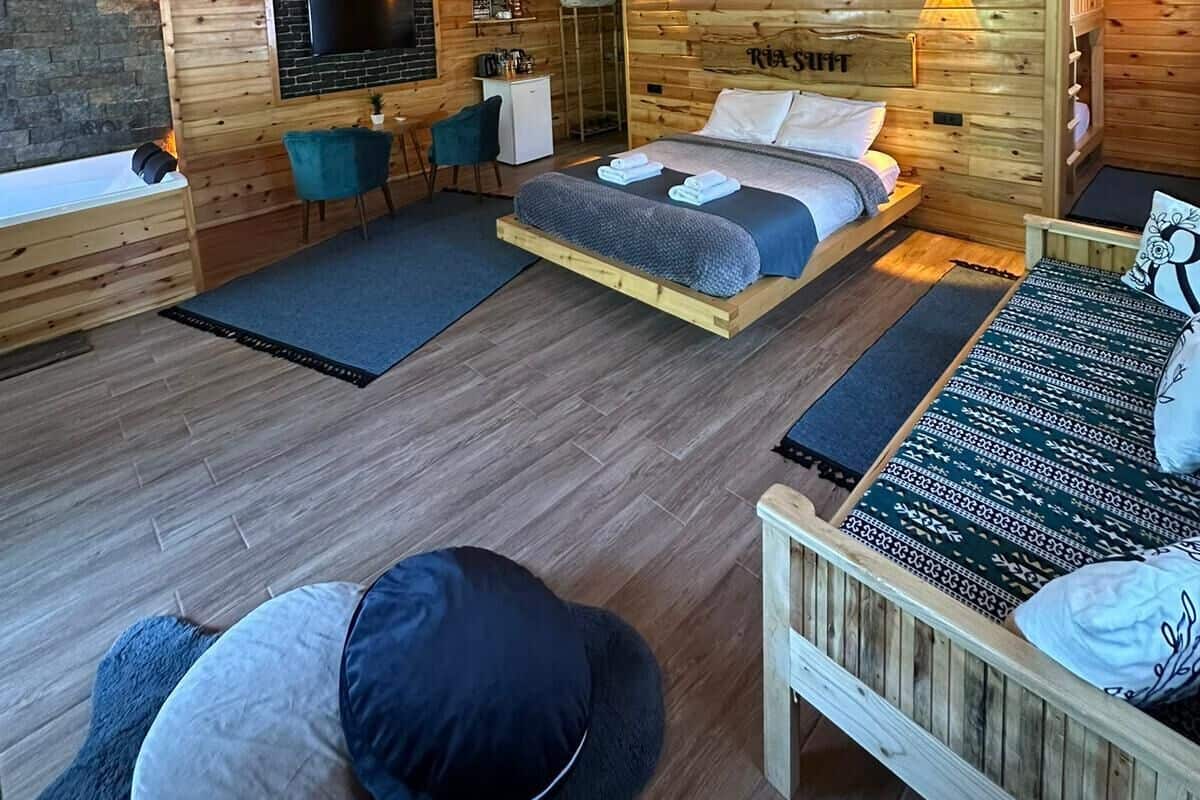 A wooden cabin interior with a bed, a sofa, a TV, and a fireplace.