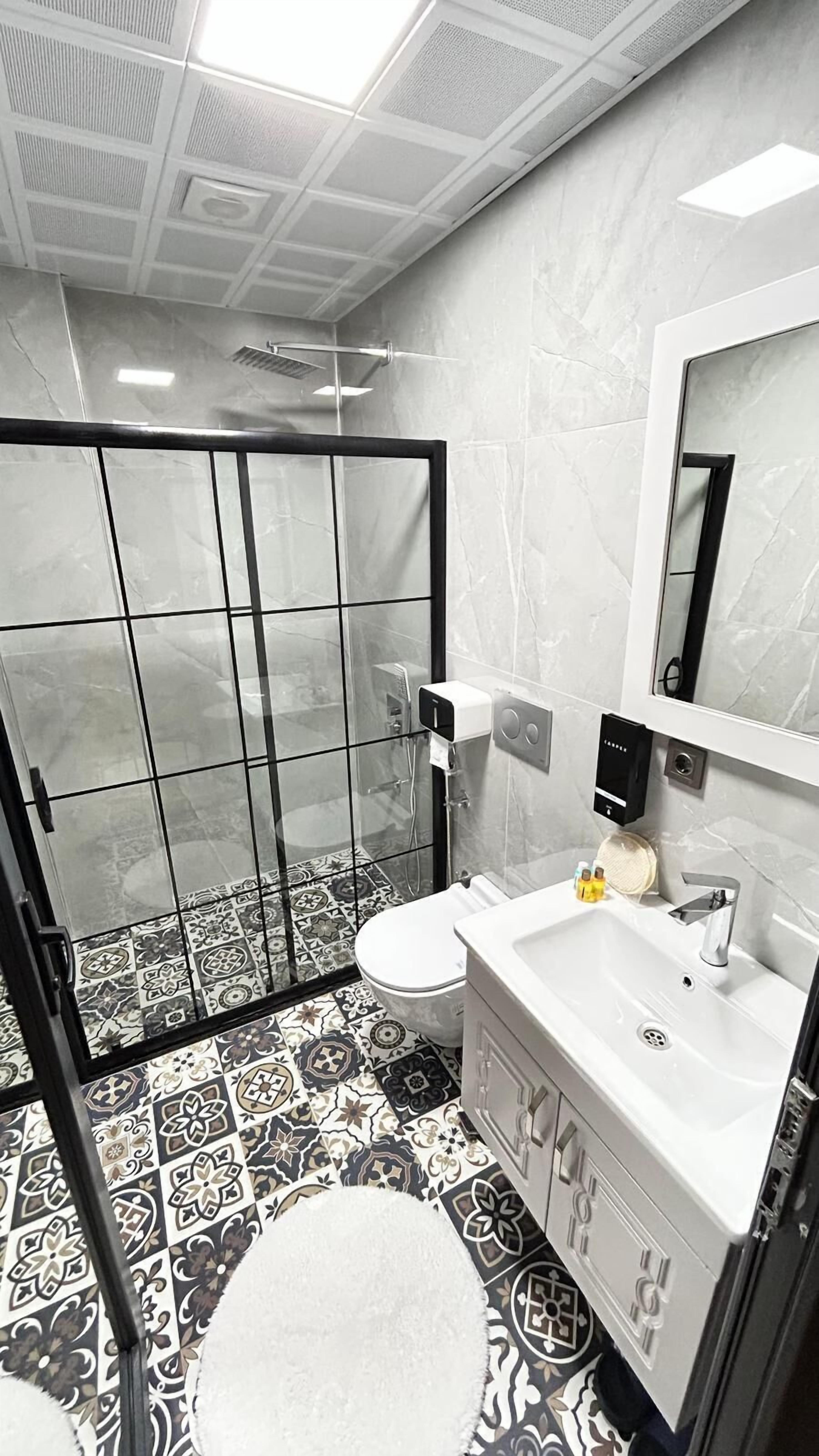 A modern bathroom with a shower, toilet, and sink.