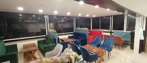 A modern lounge area with multiple seating options, large windows, and a clean, well-lit interior.
