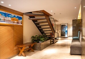 Un interior moderno con una escalera de madera, un banco y una planta en maceta.