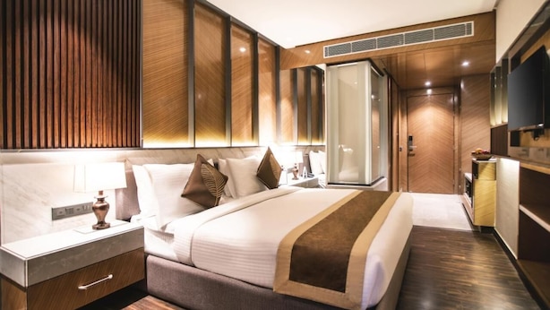 Una habitación de hotel moderna con una cama grande, una mesita de noche, un armario y un televisor.
