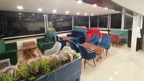 Un área de descanso moderna con diversas opciones de asientos, ventanas amplias y un interior limpio y bien iluminado.