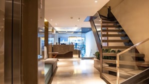 Un interior moderno con una escalera, un área de descanso y una recepción.