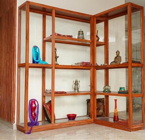 A corner room with a wooden shelving unit displaying various decorative items. - Amritara Kirpa, Amritsar Golden Temple (Amritsar)