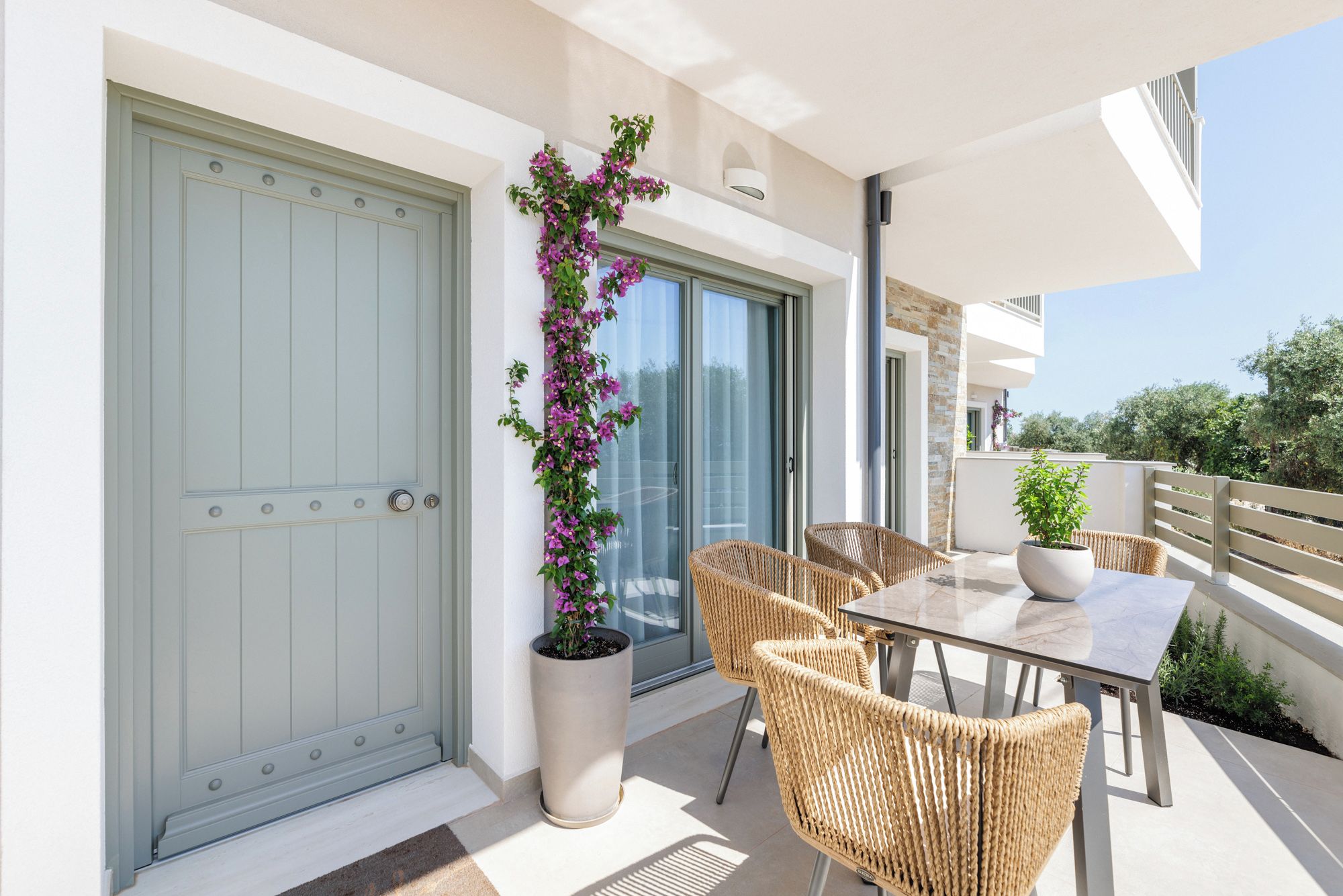A balcony with wicker furniture and a potted plant.